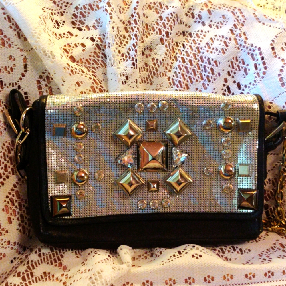 Black leather shoulder bag with decorated mesh panel.